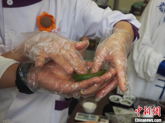 图为带教老师在“手把手”教一名留学生制作青团。　李娇阳 摄
