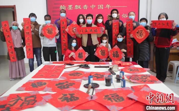 图为书法爱好者和外国留学生展示书写的春联和福字。　曹建雄 摄